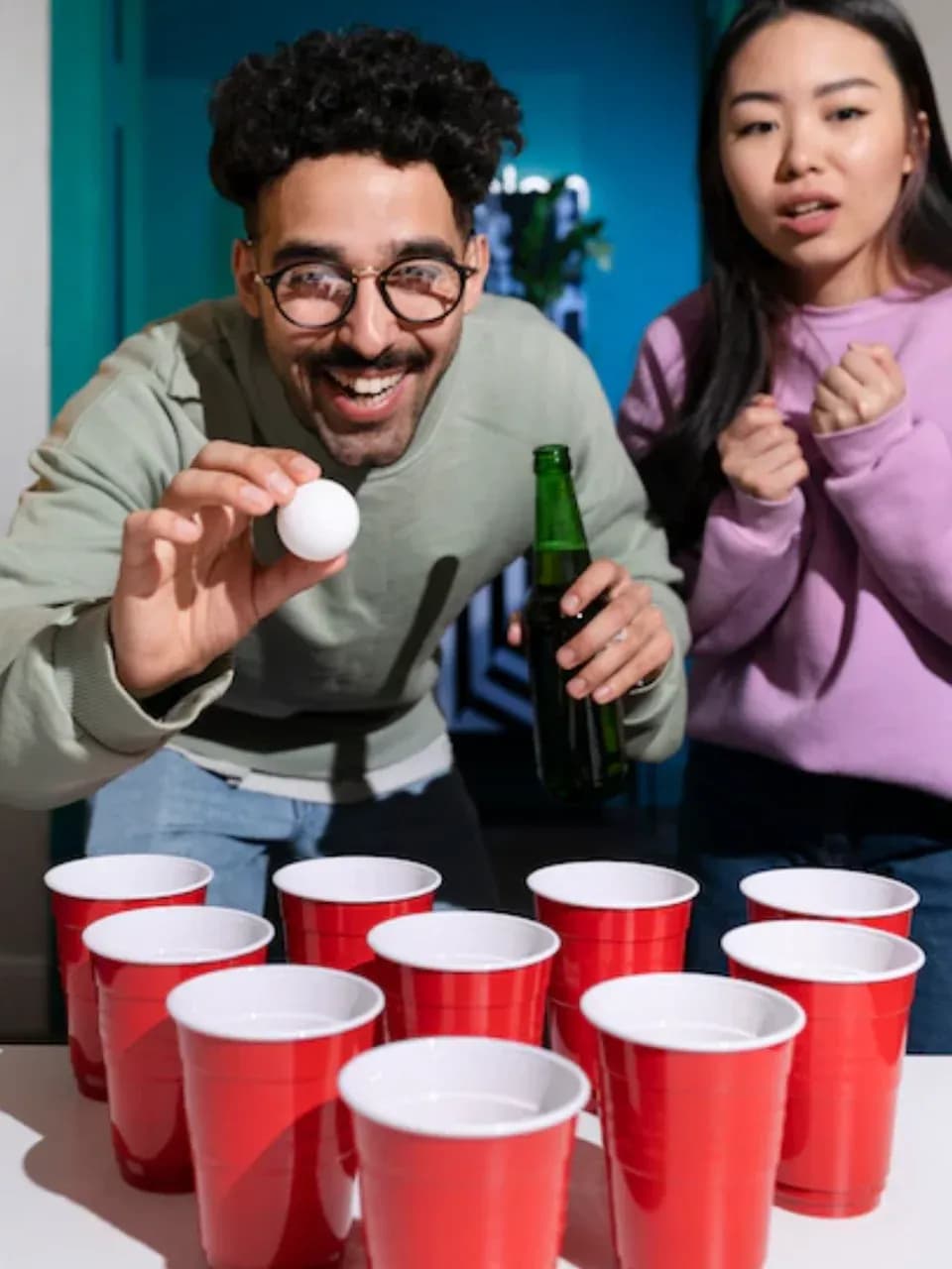 Игрок пытается попасть шариком в стаканчик в игре бирпонг