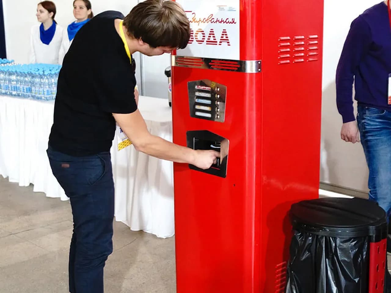 Гость наливает газировку из ретро-автомата газированной воды на мероприятии