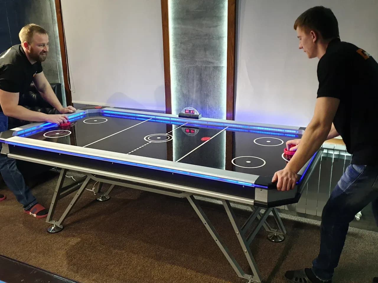 Матч в аэрохоккей: игроки у напольного стола air hockey