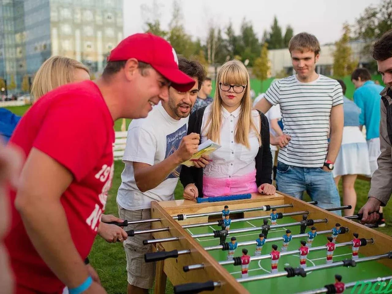 Участник играет в кикер на мероприятии. Гости болеют.
