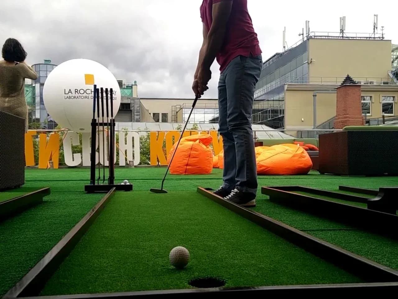 Мини гольф на улице: удар по мячу на дорожке, вид с уровня поля