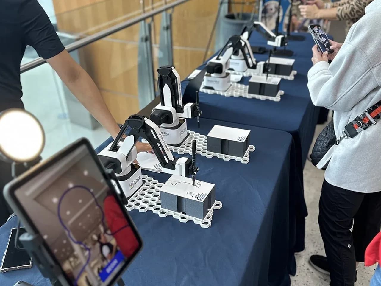 Скетч бот на мероприятии: гость снимает робота-художника во время рисования портрета