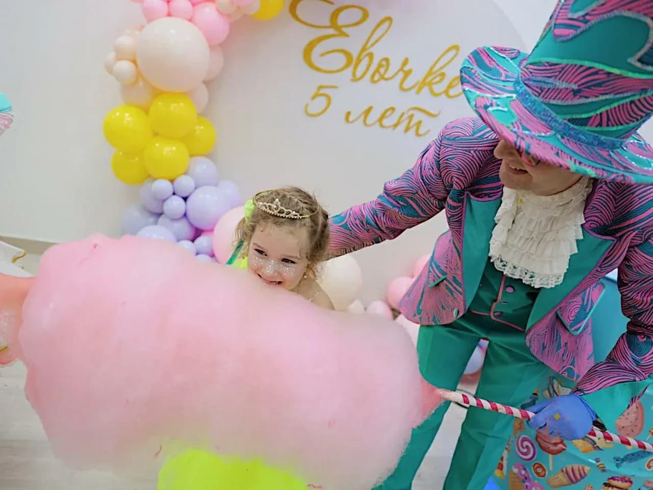 Сахарная вата на детском празднике: ребёнок получает сладкую вату у тележки