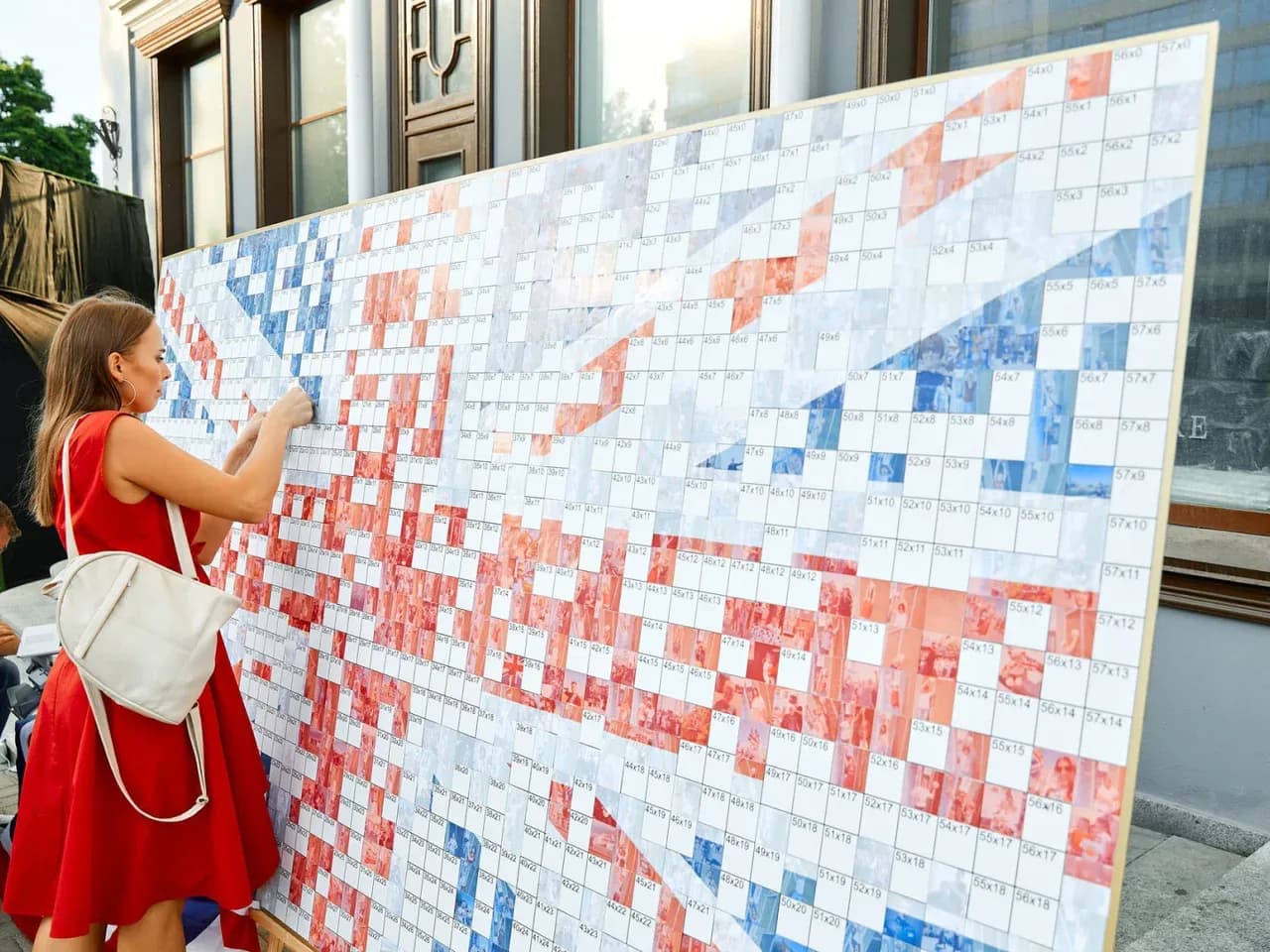 Гость на мероприятии рассматривает интерактив с фотографиями из маленьких частей