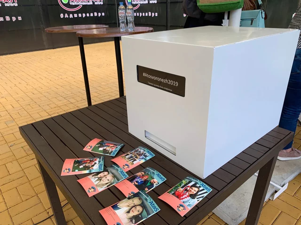 Вариант брендированного корпуса хэштег принтера на столе с готовыми фотокарточками для гостей