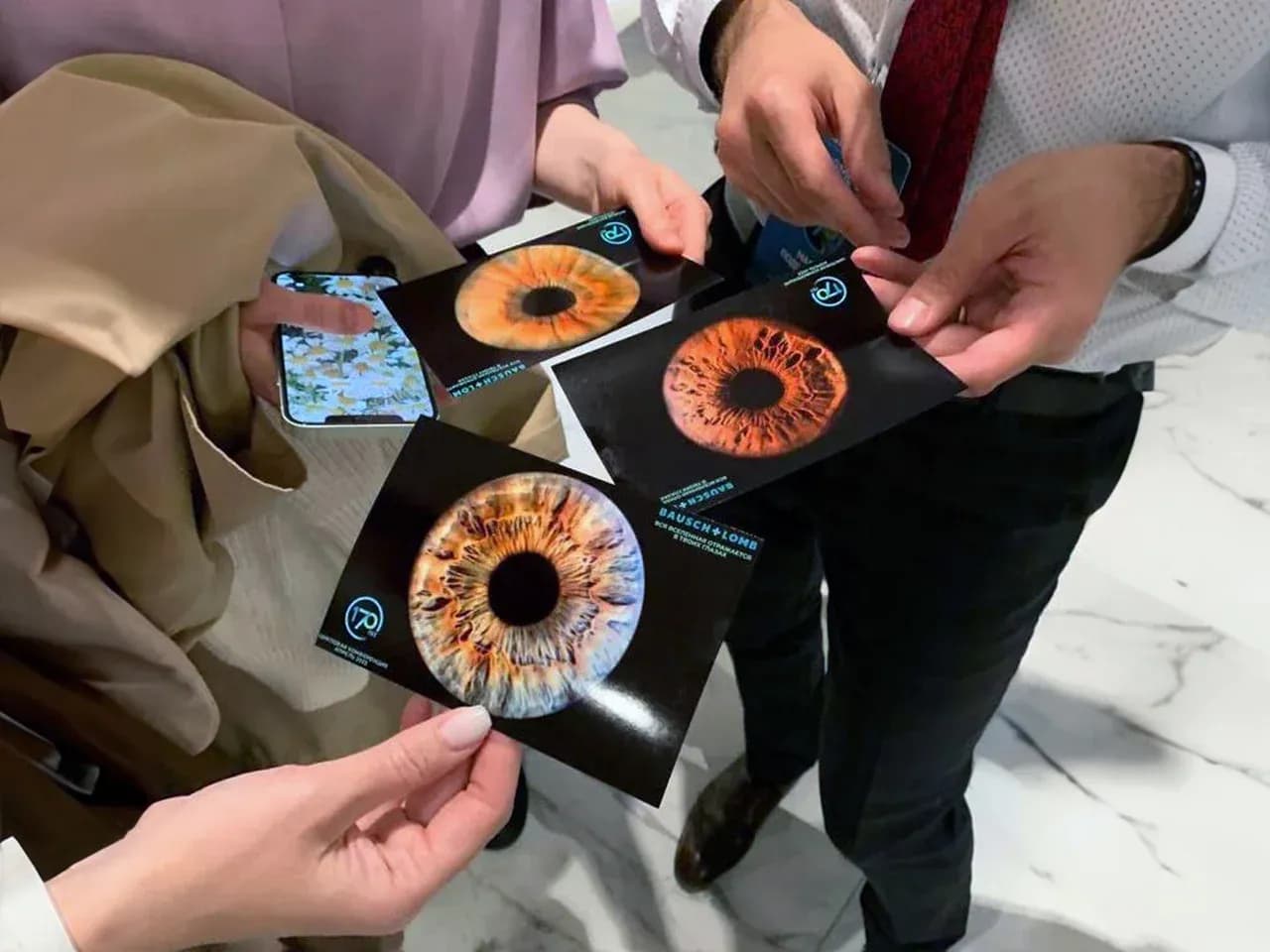 Гости держат в руках фотографии радужки глаз