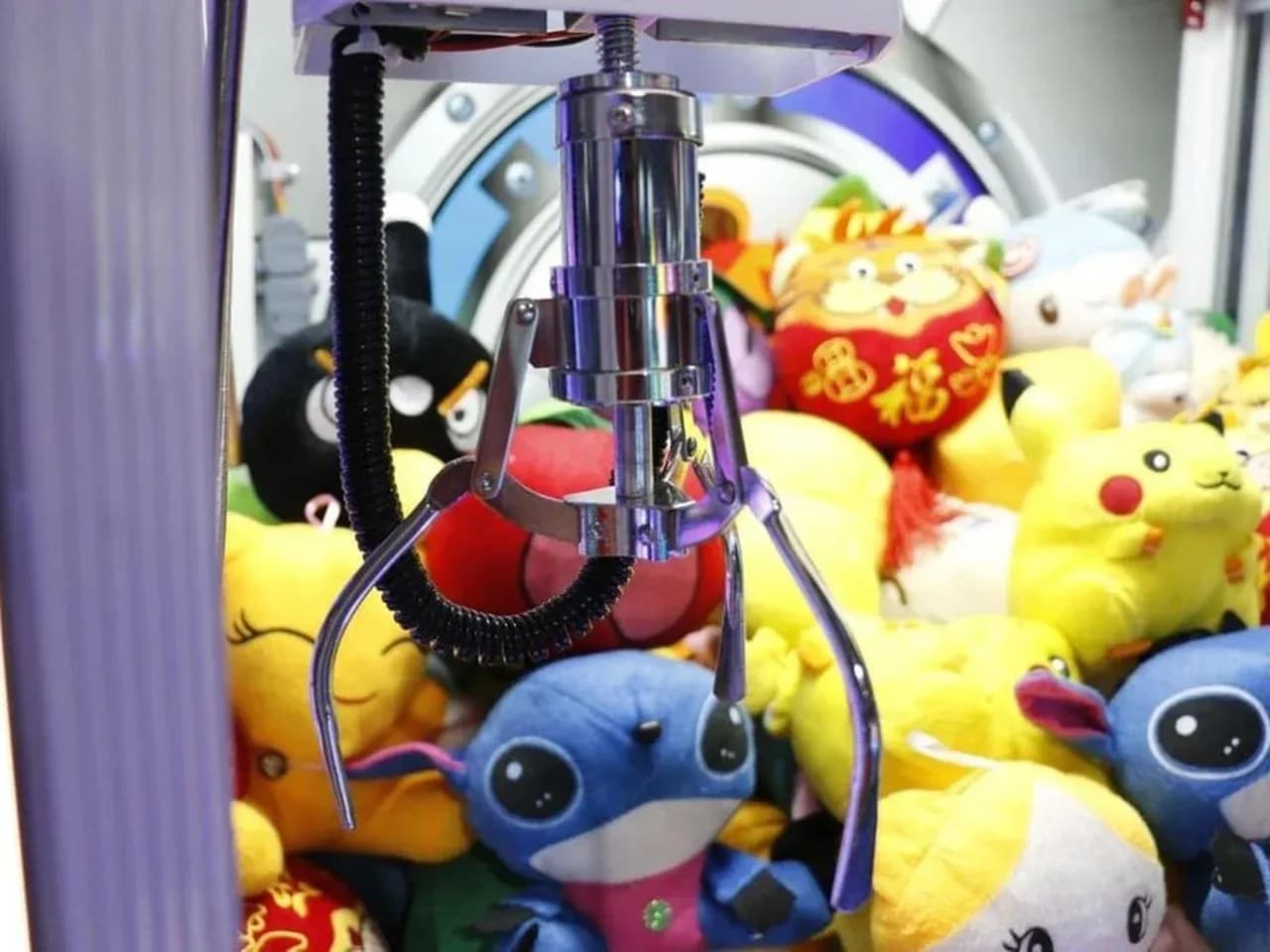 Автомат хватайка с игрушками: клешня над призами внутри игрового автомата