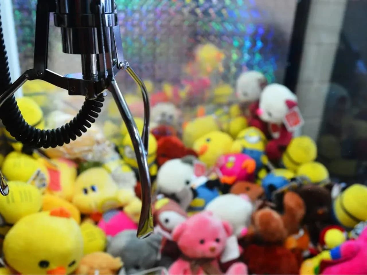 Автомат хватайка с игрушками: клешня над призами внутри игрового автомата