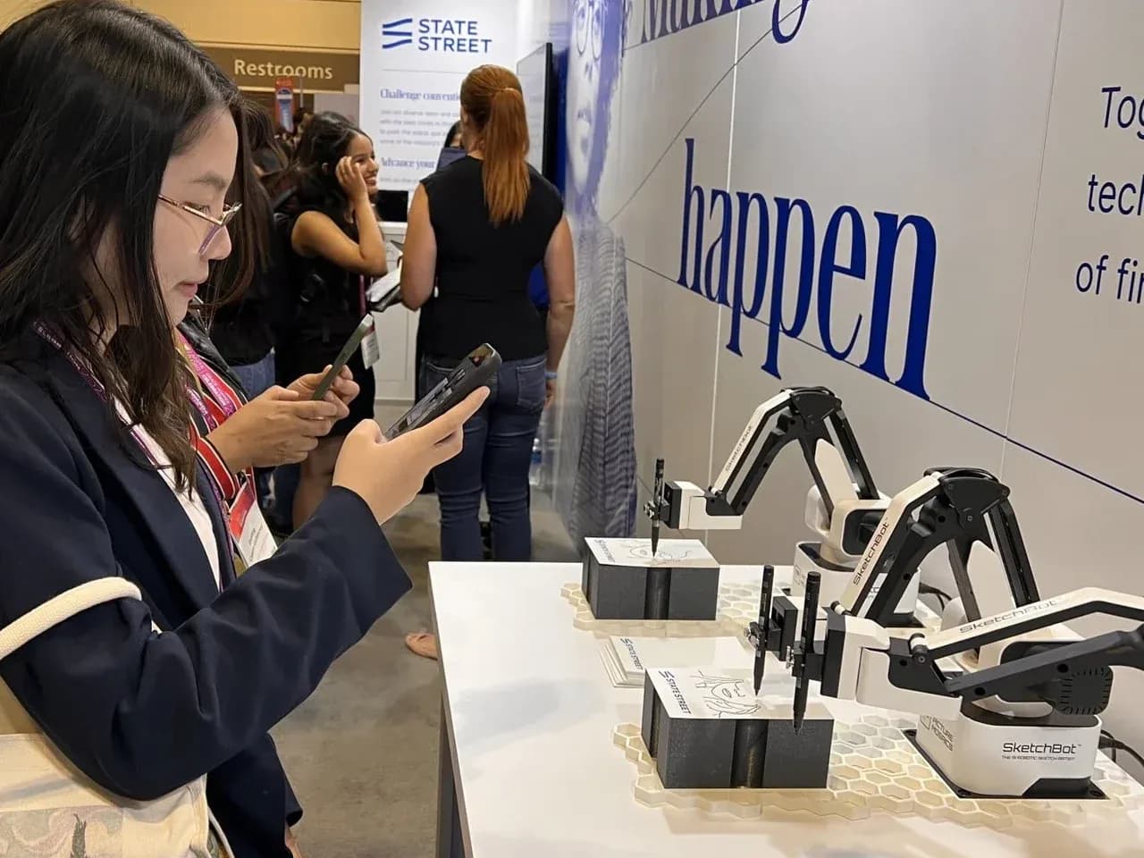 Гость фотографирует работу скетч бота: робот-художник рисует портрет