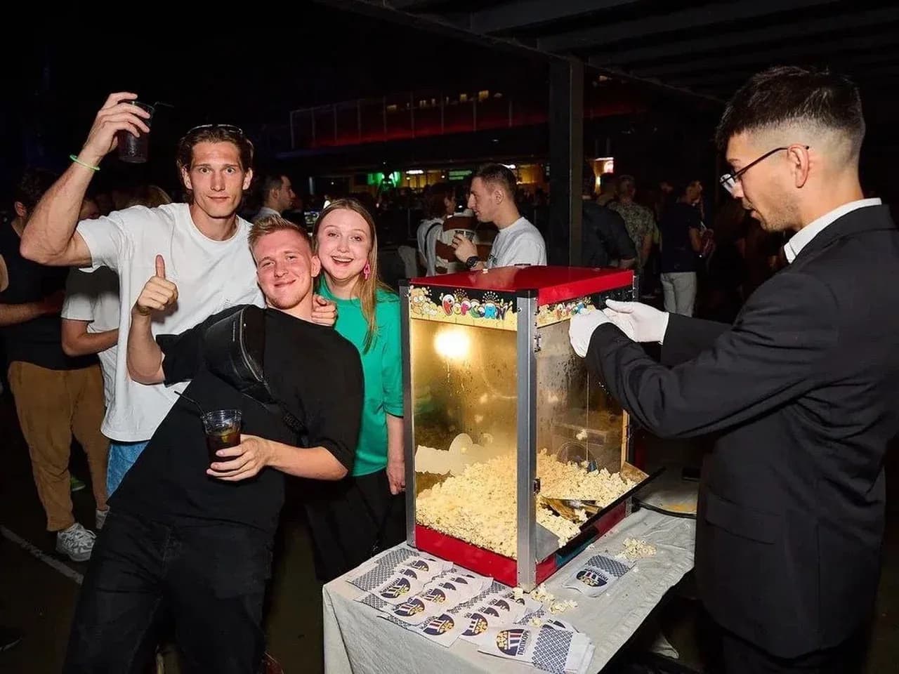 Выдача попкорна на мероприятии: тележка с попкорном и гости у стойки