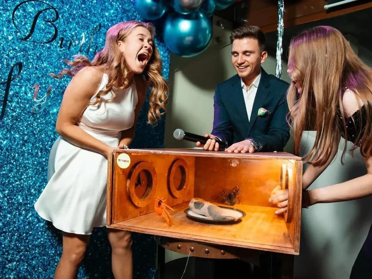 Девушки пытаются угадать, что в коробке. Ассистент помогает.